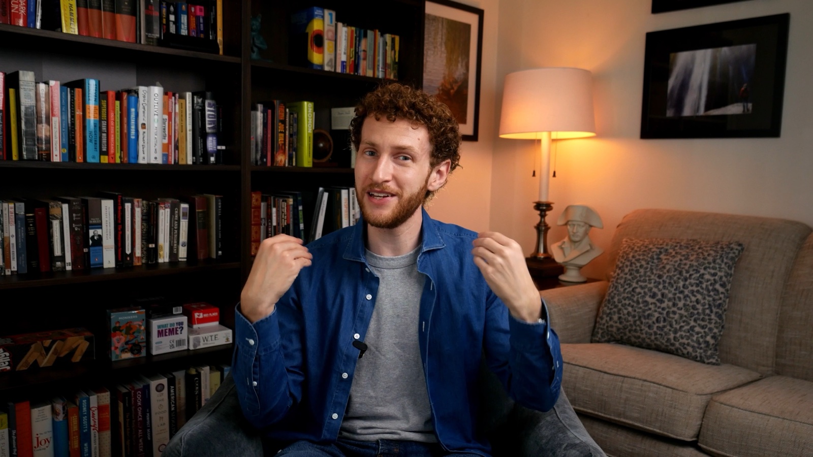 Connor talking to camera in front of his bookshelves